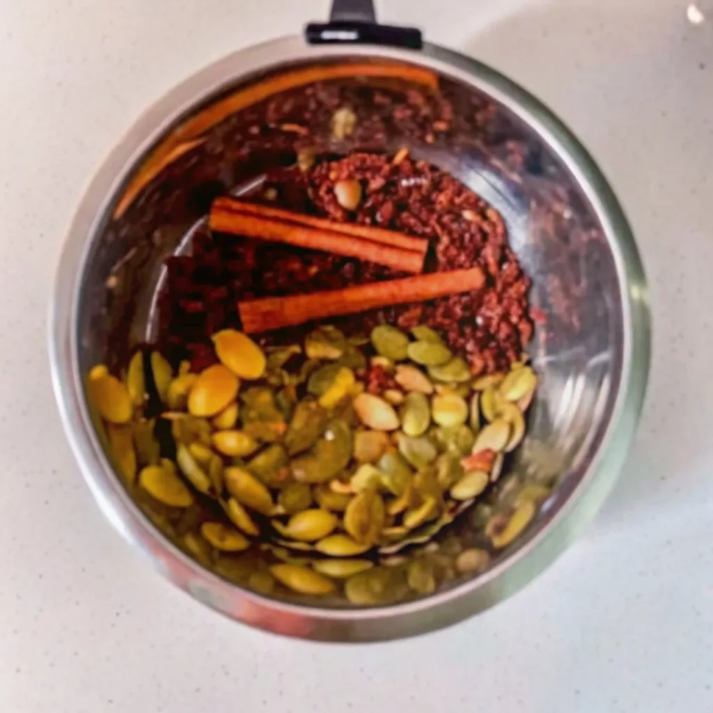 Bariatric Seed Drink Recipe: A Dietitian's Guide to the Viral Trend bariatric seed drink recipe A stainless steel bowl showing the ingredients for the bariatric seed drink recipe combined before grinding: pumpkin seeds, ground seeds, and two whole cinnamon sticks.