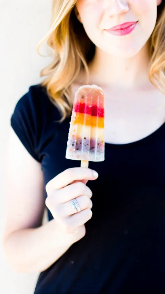 Rainbow Popsicle Dragon Fruit: The Ultimate Healthy Treat rainbow popsicle dragon fruit A woman smiling while holding a homemade rainbow popsicle with visible dragon fruit layers.